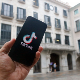Un mòbil amb el logotip de TikTok davant de l'Ajuntament de Girona