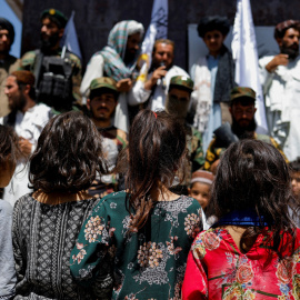 Niñas afganas observan a simpatizantes talibanes en el segundo aniversario de la caída de Kabul en una calle cerca de la embajada de EEUU en Kabul