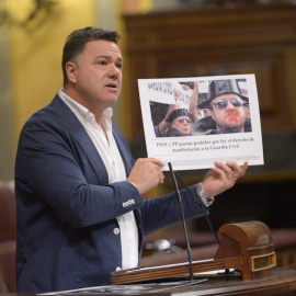 Juan Antonio Delgado, en la tribuna del Congreso, muestra una imagen de denuncia del pacto entre PP y PSOE en 2011 para negar a los guardias civiles el derecho de manifestación.
