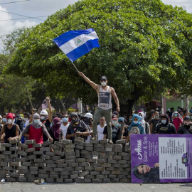 Un joven levanta una bandera de Nicaragua sobre una barricada de adoquines hoy, sábado 21 de abril de 2018, durante el cuarto día de protestas en Managua (Nicaragua). La agitación social se mantuvo hoy por cuarto día en Nicaragua pese a que el preside