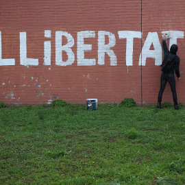 Un hombre pinta en un muro la palabra "LLIBERTAD" en Barcelona.REUTERS/Albert Gea