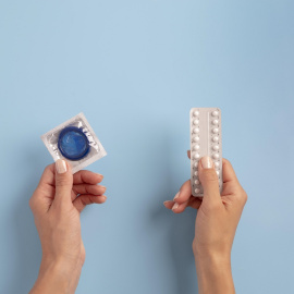 Unas manos sujetan unas pastillas y un condón