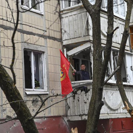 Un hombre ondeando una bandera roja desde el balcón de un edificio dañado tras un bombardeo en el centro de Belgorod, Rusia, el 16 de marzo de 2024.