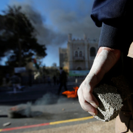 Un palestino sujeta una piedra mientras mira los disturbios con las fuerzas de seguridad israelíes.REUTERS/Mussa Qawasma