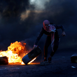 Un palestino sujeta un neumático en llamas durante las protestas producidas tras el reconocimiento de Jerusalén como capital de Israel por parte de Trump./REUTERS