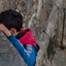 Un menor extranjero no acompañado, en las escolleras del puerto de Melilla.- JOSÉ PALAZÓN /FUNDACIÓN RAÍCES
