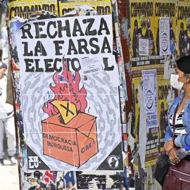 Una mujer camina junto a carteles que piden el voto negativo en el referéndum.