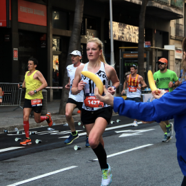 17-3-2023 Una voluntària ofereix un plàtan a una participant mentre corre a la Marató de Barcelona
