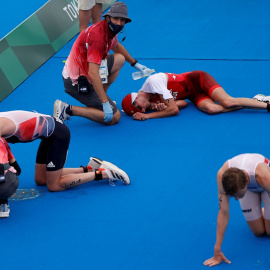 26/07/2021.- Jonathan Brownlee (i) de Gran Bretaña, Max Studer (c) de Suiza y Casper Stornes de Noruega descansan en el suelo tras cruzar la meta del triatlón masculino durante los Juegos Olímpicos 2020, este lunes en el parque marino de Odaiba en Toki