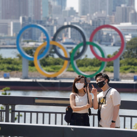 Una pareja se toma fotos frente a los anillos olímpicos en Tokio. EFE/Kai Föersterling