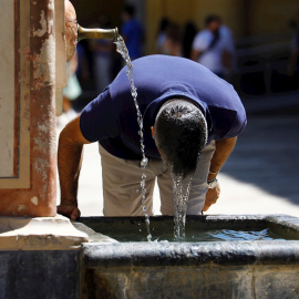 Un visitante se refresca en una fuente del Patio de los Naranjos de la Mezquita Catedral de Córdoba este sábado, en una jornada de intenso calor en la ciudad andaluza.