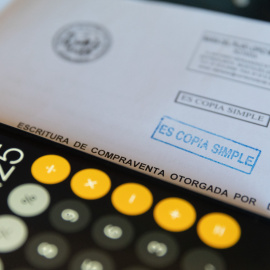 Una calculadora y una escritura de compraventa de una hipoteca, a 2 de junio de 2022, en Madrid.