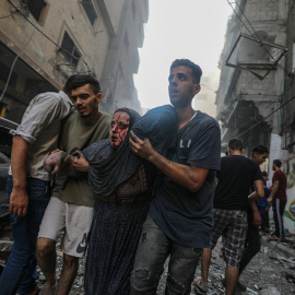 Una mujer recibe ayuda para salir de una zona bombardeada por Israel en el campo de refugiados de Al-Shati, en el oeste de la ciudad de Gaza, a 14 de octubre de 2023.