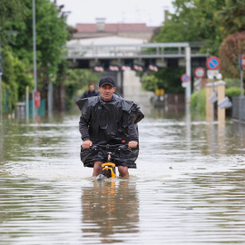 Un hombre monta en bicicleta en mitad de las inundaciones provocadas por las lluvias torrenciales de mayo en Emilia-Romagna, en Italia.