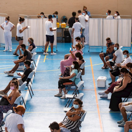Multitud de jóvenes aguardan sentados tras recibir la vacuna contra el coronavirus en el pabellón municipal de Espartinas (Sevilla).