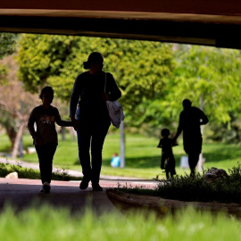 Foto de archivo de unos padres paseando por un parque con sus hijos.