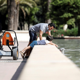 Un padre y su hijo se refrescan en una fuente de Valencia.