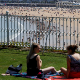 Dos jóvenes disfrutan junto a la playa de La Concha de San Sebastián.