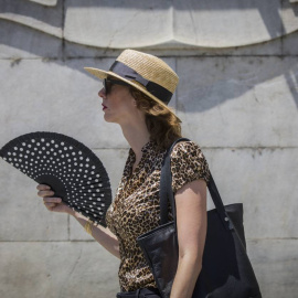 Una mujer se abanica mientras camina por la Avenida de la Constitución, en Sevilla.