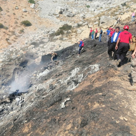 Miembros de los equipos de búsqueda y rescate inspeccionan el avión anfibio ruso Be-200 estrellado.