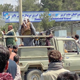 Los talibanes montan guardia frente al aeropuerto internacional Jamid Karzai mientras la gente camina hacia el aeropuerto para huir del país.