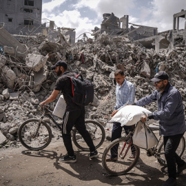 28/04/2024 Palestinos caminan frente a la destrucción en el campo de Nuseirat, en la Franja de Gaza, a 27/04/2024.