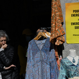 Una mujer, en un tienda de ropa con un cartel que reza 'Pobreza Energética = Emergencia Social', en una imagen de archivo.