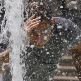 Un hombre se refresca en una fuente de Córdoba.