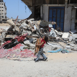 19/04/2924 Un niño palestino sostiene madera junto a las ruinas de edificios destruidos por los bombardeos israelíes, a 13 de abril de 2024.