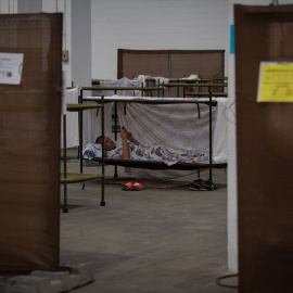 Un hombre descansa en su cama en el interior de las instalaciones del albergue de Fira Barcelona, habilitado por la pandemia para 225 personas sin techo, a 28 de marzo de 2020.