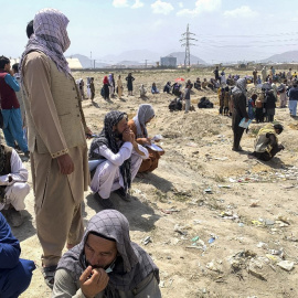 Afganos se reúnen mientras esperan para subir a un avión militar estadounidense para salir del país.