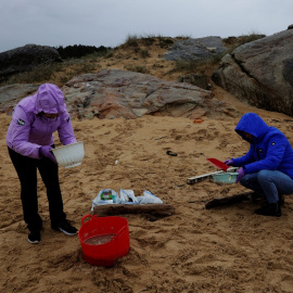 Un grupo de voluntarios trabaja en la limpieza de la playa de Vilar, en A Coruña, contaminada por miles de pellets de plástico.