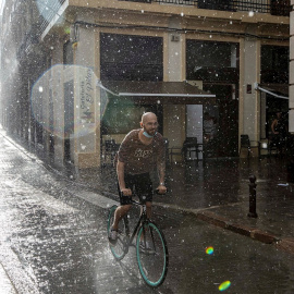 Una persona circula en bicicleta bajo una fuerte tromba de agua en València.