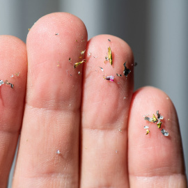 Una mano muestra restos de microplásticos.