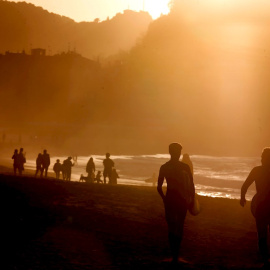 Surfistas y personas pasean por la playa de la Zurriola de Donosti.
