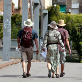 Tres turistes amb el cap cobert amb barrets per la calor, a Lleida.