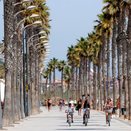 Varias personas pasean en bicicleta por el paseo de la playa de La Patacona De Alboraya (Valencia