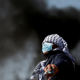18/02/2022 Un manifestante con el rostro cubierto mira durante una protesta contra los asentamientos judíos en la aldea de Beta, cerca de Naplusa, en la Cisjordania ocupada por Israel