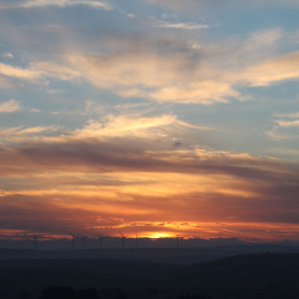 Un cielo con el sol atardeciendo entre nubes.