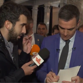 Captura del vídeo en el que el reportero Isma Juárez le pasa a Pedro Sánchez un décimo por la espalda