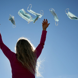 23/2/22-Una mujer tira mascarillas al aire, a 8 de febrero de 2022, en Madrid (España).