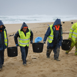 Operarios retiran los pellets o bolitas para fabricar plástico que han aparecido en las playas gallegas y de Asturias.