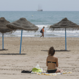 Una mujer toma el sol en una playa de Valencia.