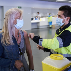 Un sanitario vacuna a una mujer con la dosis de Pfizer, en el Wanda Metropolitano, a 19 de mayo de 2021, en Madrid