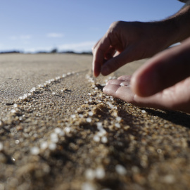 Una persona recoge pellets en la playa de Mera, situada en el concello coruñés de Oleiros, a 12 de enero de 2024.