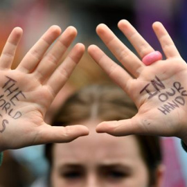 "El mundo está en nuestras manos", es la leyenda escrita a bolígrafo que muestra en las palmas de sus manos un estudiante que participa en el acto de protesta "School Strike 4 Life" en Sidney, Australia, este viernes.