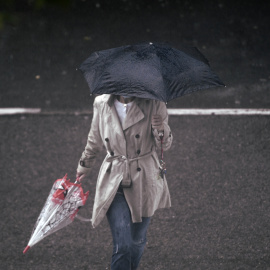 Una persona camina bajo la lluvia protegida con un paraguas, en Madrid (España).