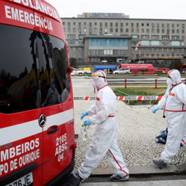 Trabajadores de la salud con trajes de protección pasan junto a una ambulancia en el nuevo centro de clasificación para pacientes con coronavirus en el Hospital Santa María, Lisboa, a 29 de enero de 2021.