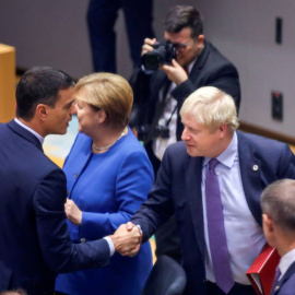 El presidente del Gobierno en funciones, Pedro Sánchez, saluda al primer ministro británico, Boris Johnson, en presencia de la canciller alemana Angela Merkel, al comienzo de la cumbre de la UE en Bruselas, en la que se ha dado el visto bueno al nuevo a