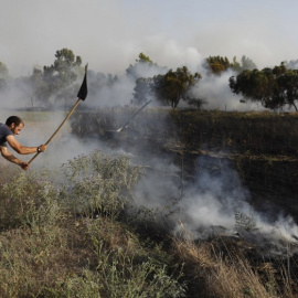 Un hombre apaga un incendio en Kibbutz de Kissufim, a lo largo de la frontera con la Franja de Gaza,  provocado por material inflamable adherido a un globo de helio. / AFP - MENAHEM KAHANA